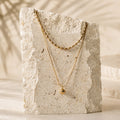 Goudkleurige layered ketting Indigo Necklace van hi SISU op travertin steen