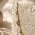 Gouden chain ketting met zonhangers op travertin steen, close-up