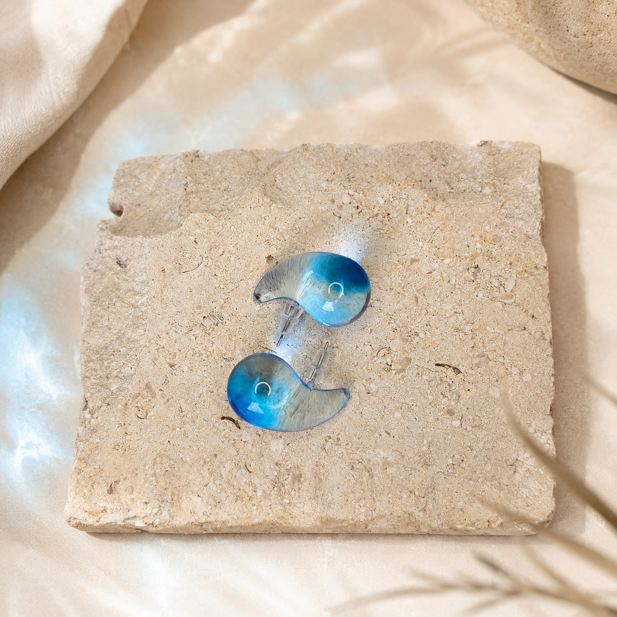 Blauwe semi-transparante oorbellen Charlotte Earrings van hi SISU op travertin steen