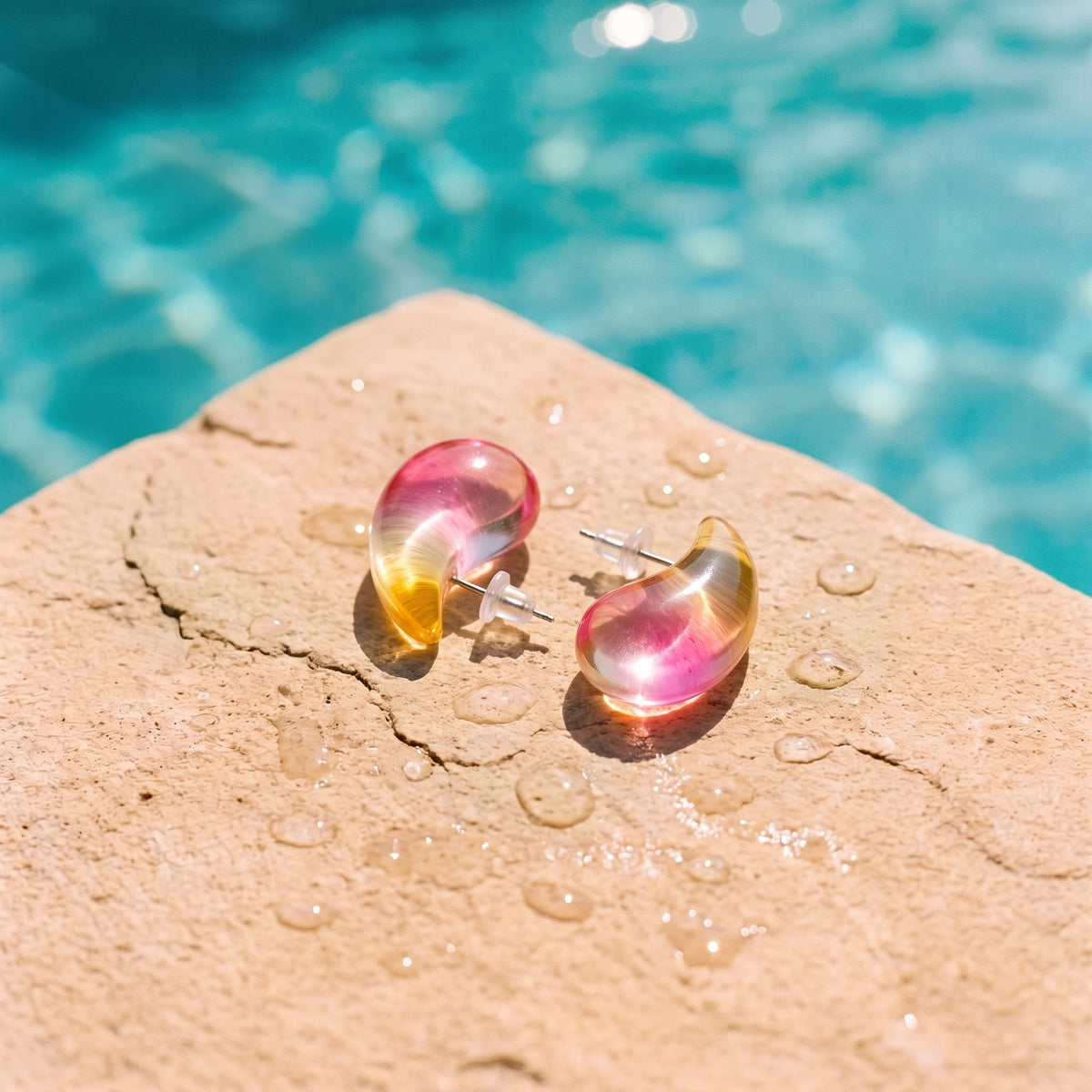 Roze semi-transparante druppel oorbellen Charlotte Earrings van hi SISU aan de rand van een zwembad