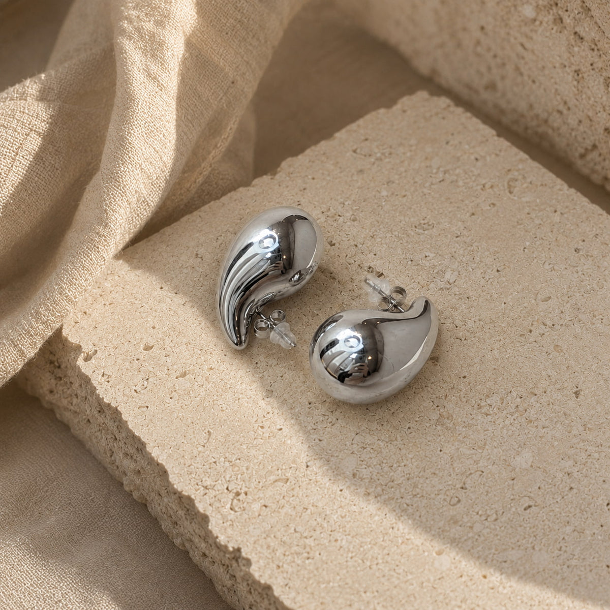 Zilveren druppel oorbellen Isabel Earrings van hi SISU, close-up op travertin steen
